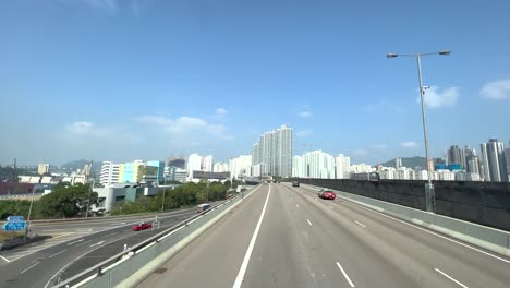 elevated highway where cars are taking over with in the background the high skyline of hong kong on a sunny day