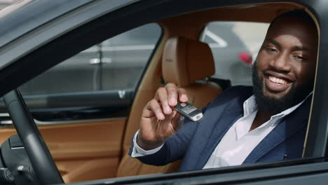 closeup african man sitting front at car. businessman taking key at vehicle