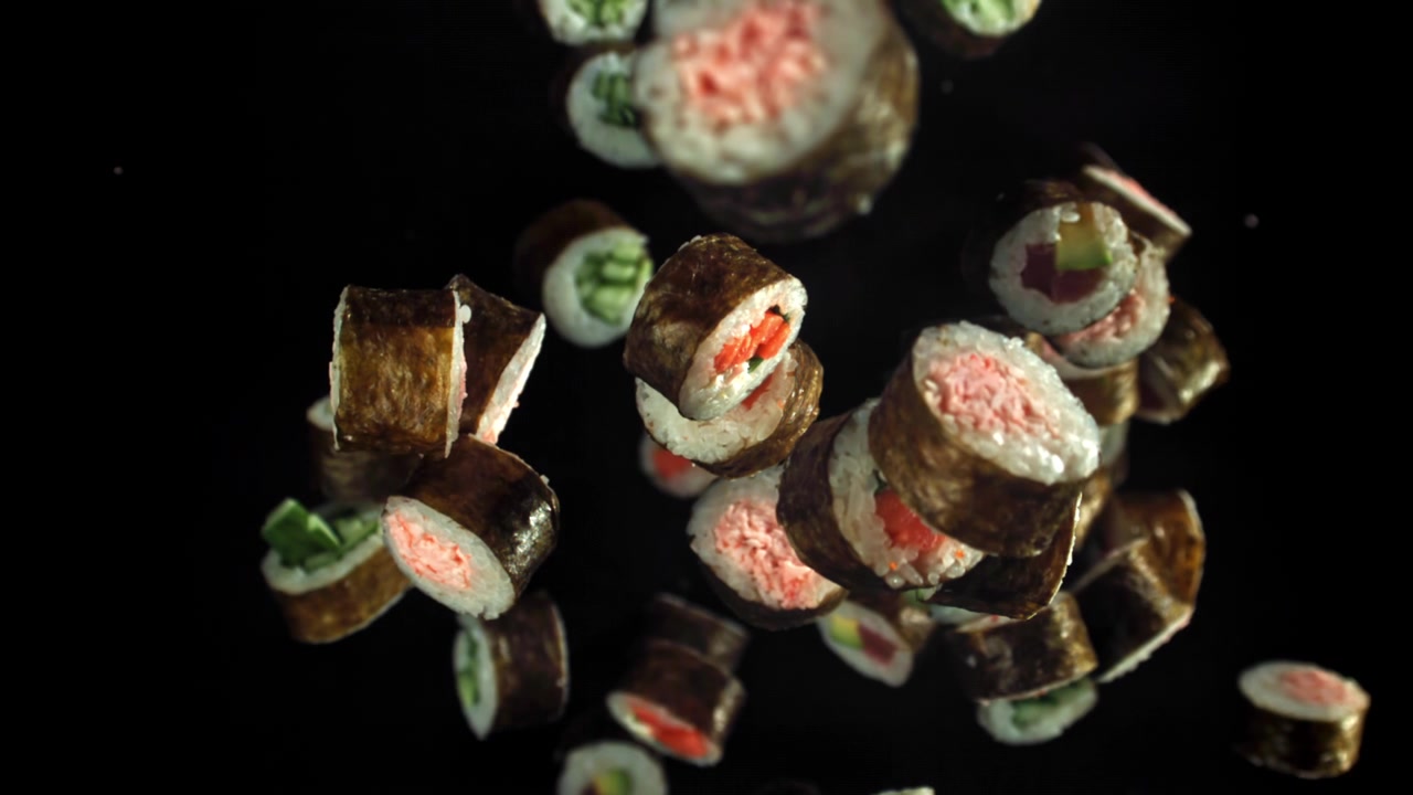 Verschiedene frische Sushi-Rollen fallen in Zeitlupe