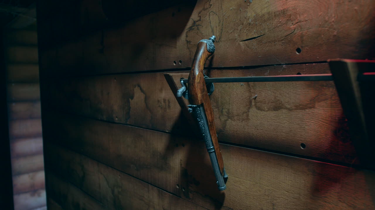 An antique flintlock pistol hanging on a wooden wall of a pirate ship, secured by a simple metal mount.