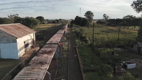 aerial drone view of abandoned railway tracks with long line of abandoned cargo wagons