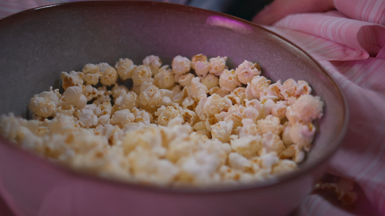 Woman hands grabbing popcorn in bowl closeup. Unrecognizable girls taking snack