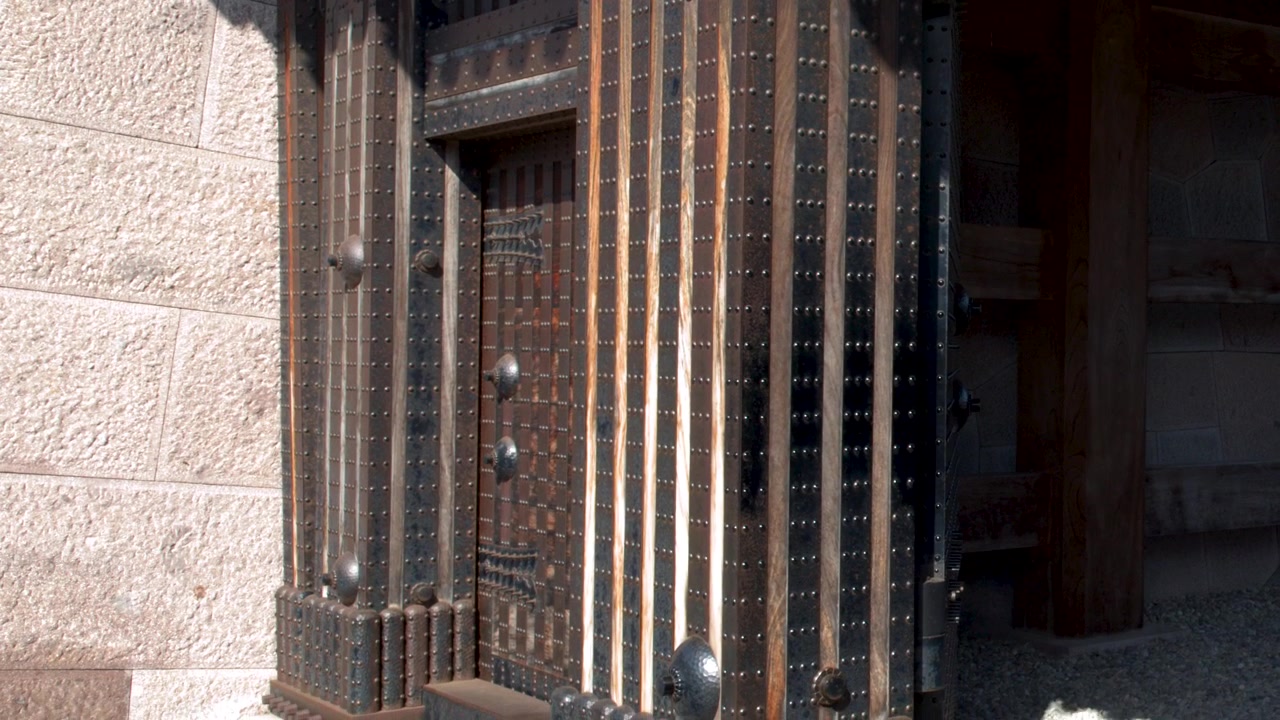 Inquadratura media statica di un cancello di legno storico e un muro di pietra sotto il sole splendente