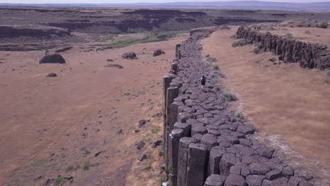 hiker walks atop dramatic volcanic basalt rock columns in wa state