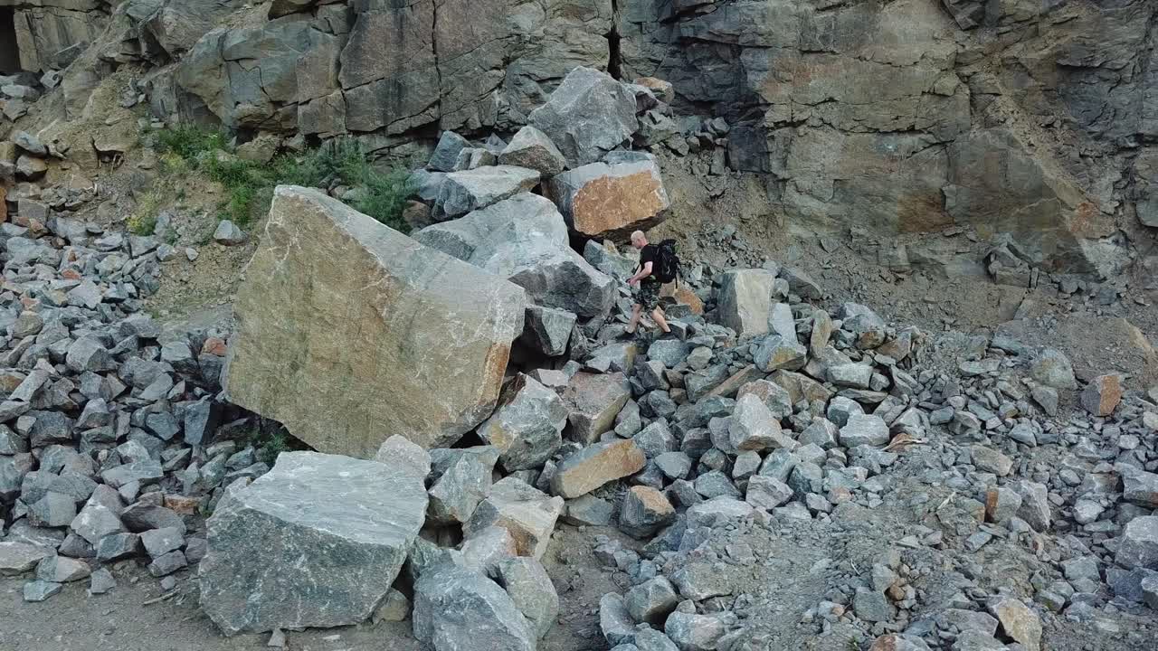 Man Walking along Giant Rocky Mountain Wall. Travel concept. Aerial view