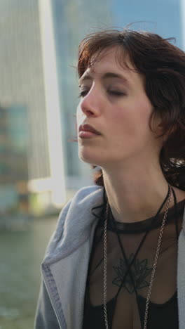 Vertical-Video-Outdoor-Fashion-Portrait-Of-Young-Alternative-Style-Woman-With-Tattoos-And-Piercing-Standing-Outside-Modern-Buildings-At-Canary-Wharf-London-Shot-In-Real-Time-4