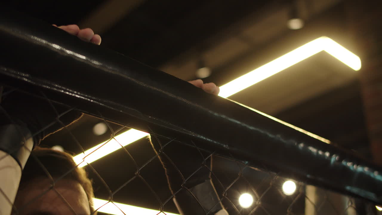 hombre irreconocible apoyado en la rejilla en el club deportivo. persona masculina descansando en el gimnasio