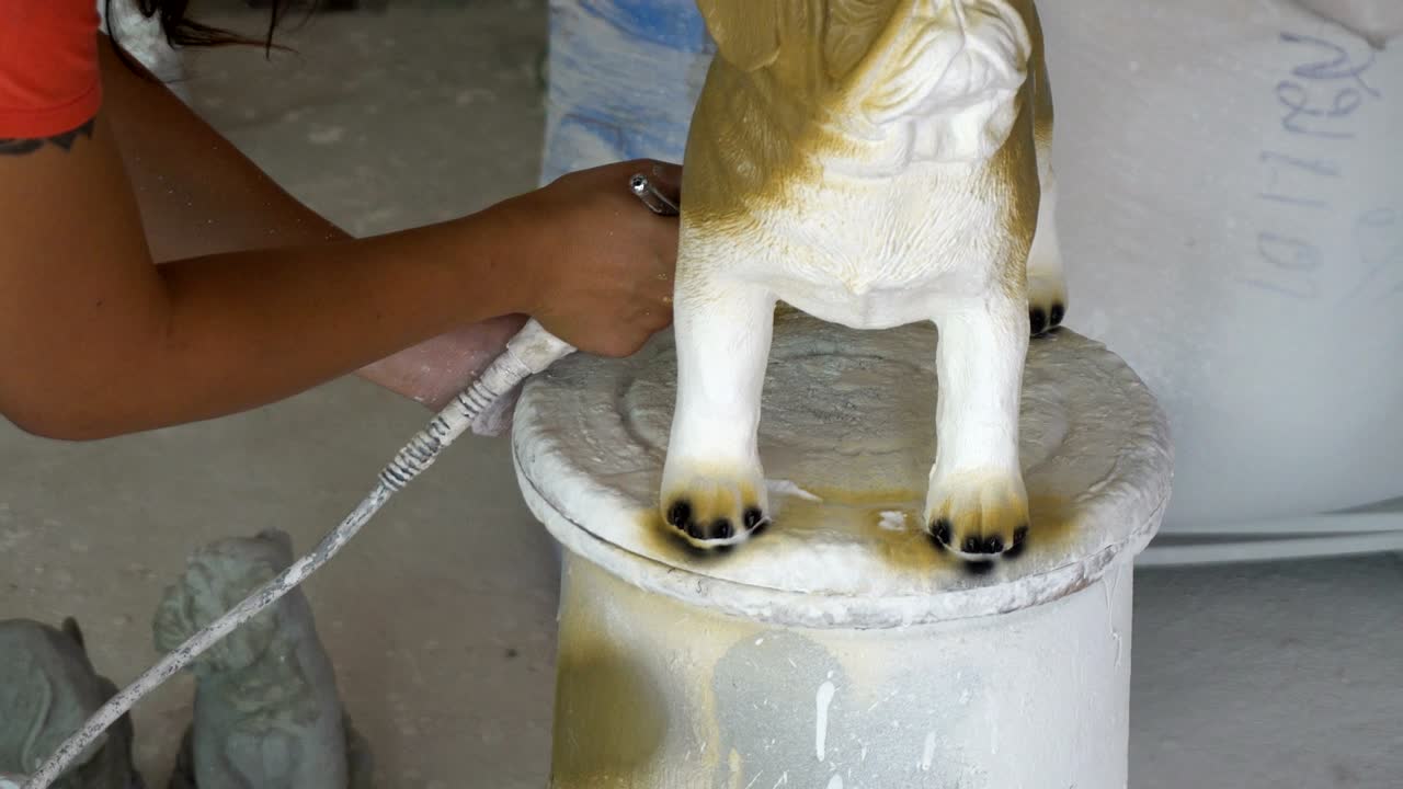 mujer con mano en guante pintado estatua de perro pug detalles por aerógrafo