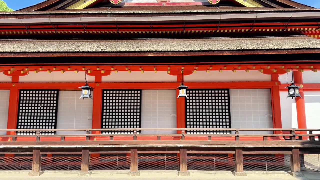 Traditional Japanese shrine exterior with vivid red pillars and wooden railings in sunlight