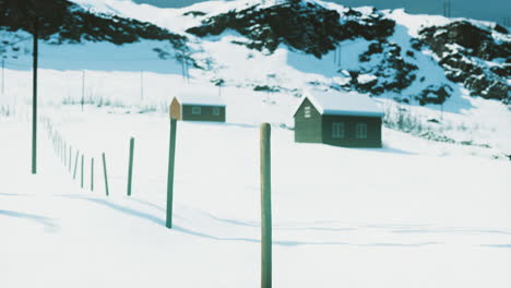 snow covered landscape with distant cabins in a mountainous region