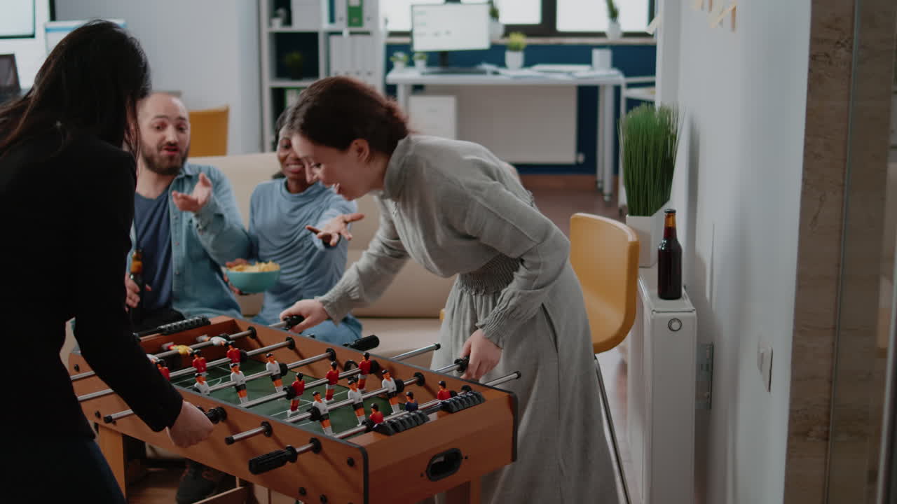 Corporate workmates using foosball table to play soccer game
