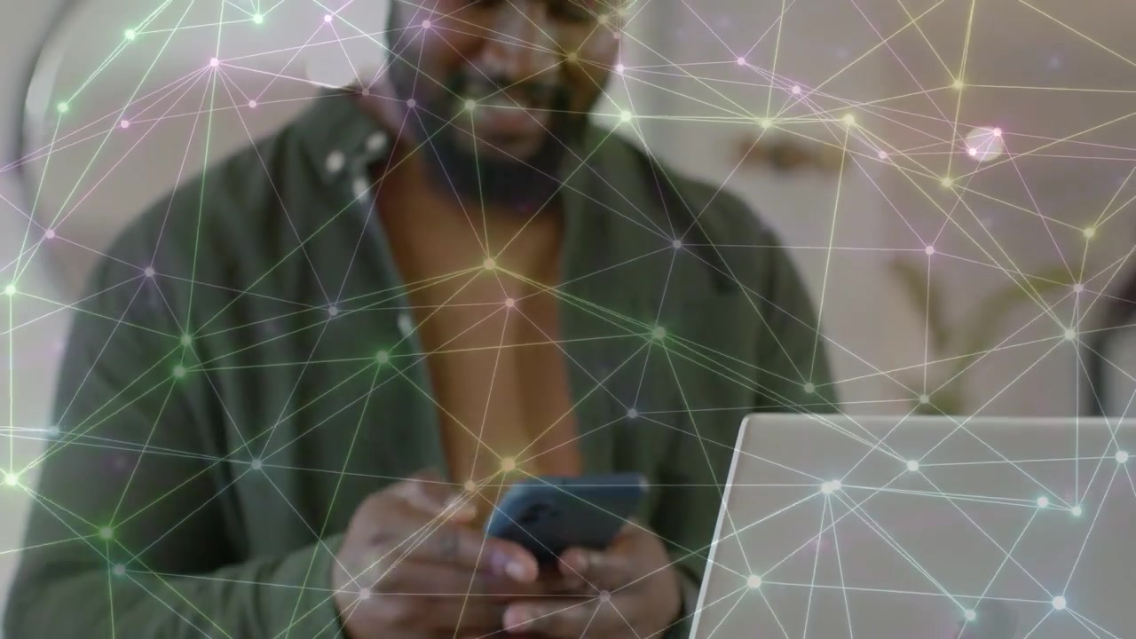 Homme passant de l'ordinateur portable au téléphone, tapant sur le téléphone pour les affaires tandis qu'une superposition de réseau relie les appareils