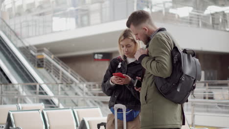 couple checking phone at airport terminal