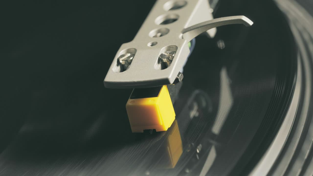 비닐 플레이어 턴테이블: 회전하는 비닐 레코드의 조각, 바늘을 클로즈업으로 가진 스타일러스, 바늘과 비닐 판을 클로스업으로 멈추는.