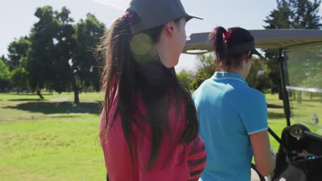 Two-caucasian-women-playing-golf-going-into-a-golf-cart