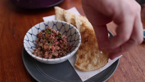 hand picking bread from plate with food