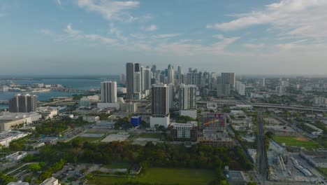 backwards fly above city. group of modern high rise apartment or office downtown buildings on waterfront. miami, usa