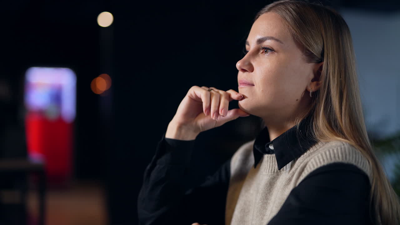 Pretty woman sitting and thinking over something. Female entrepreneur filling stressed after a long working day. Close up. Dark blurred backdrop.