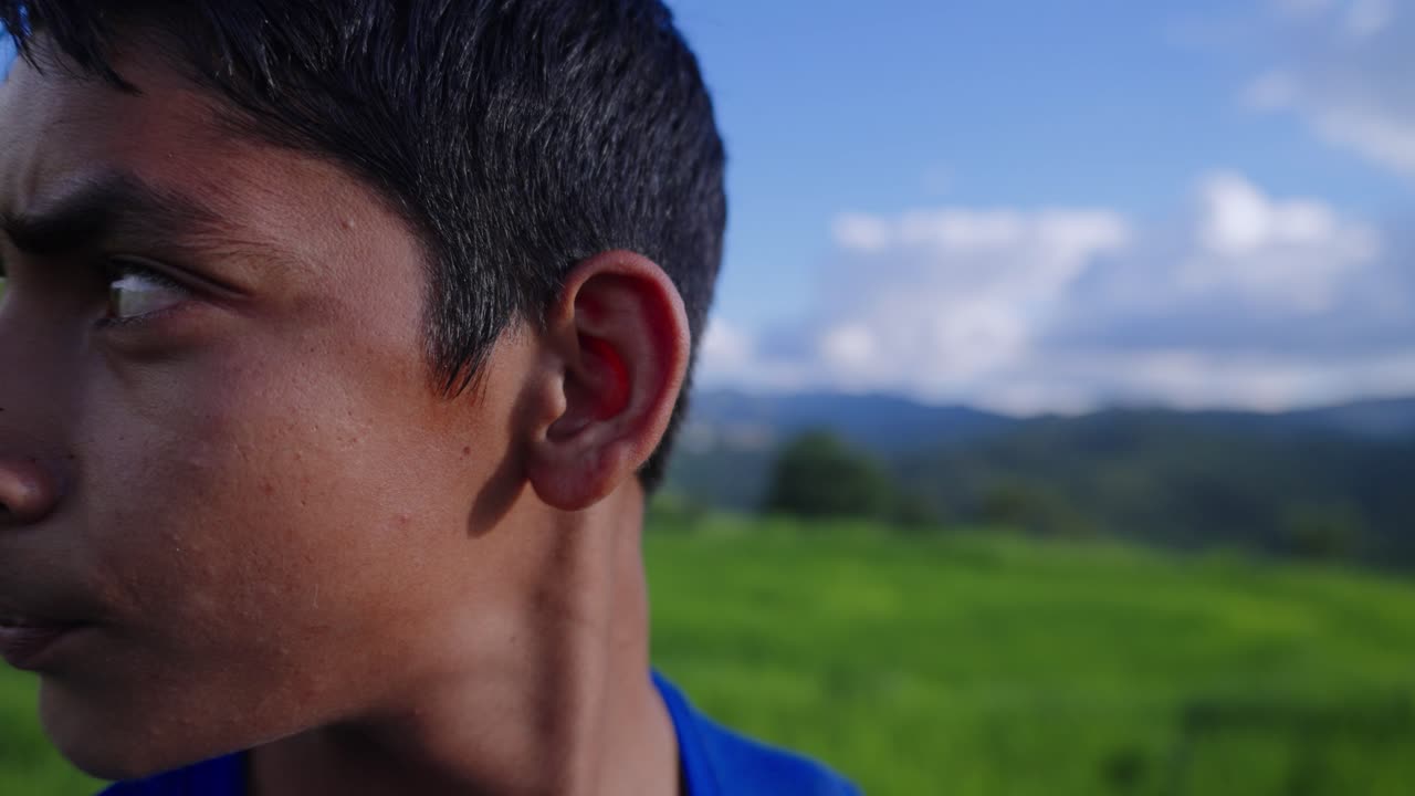 Indian village kid looking anxious in vibrant green field, eyes darting side to side, dramatic close-up, 4k video