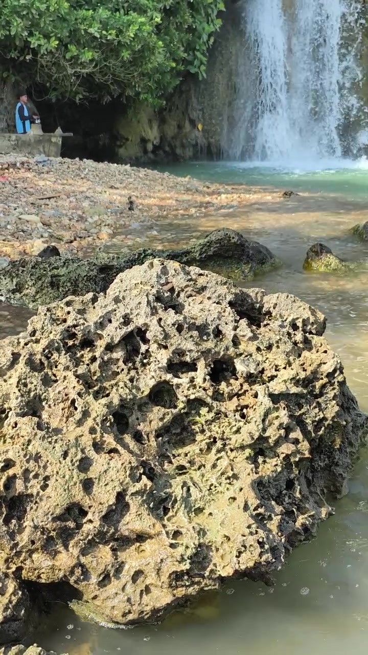 Roccia porosa in primo piano di una cascata tropicale