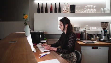 girl working and sitting at reception, typing computer keyboard, side view