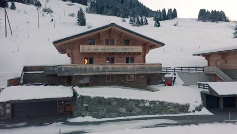 drone slowly flying towards luxurious chalet in snow covered landscape