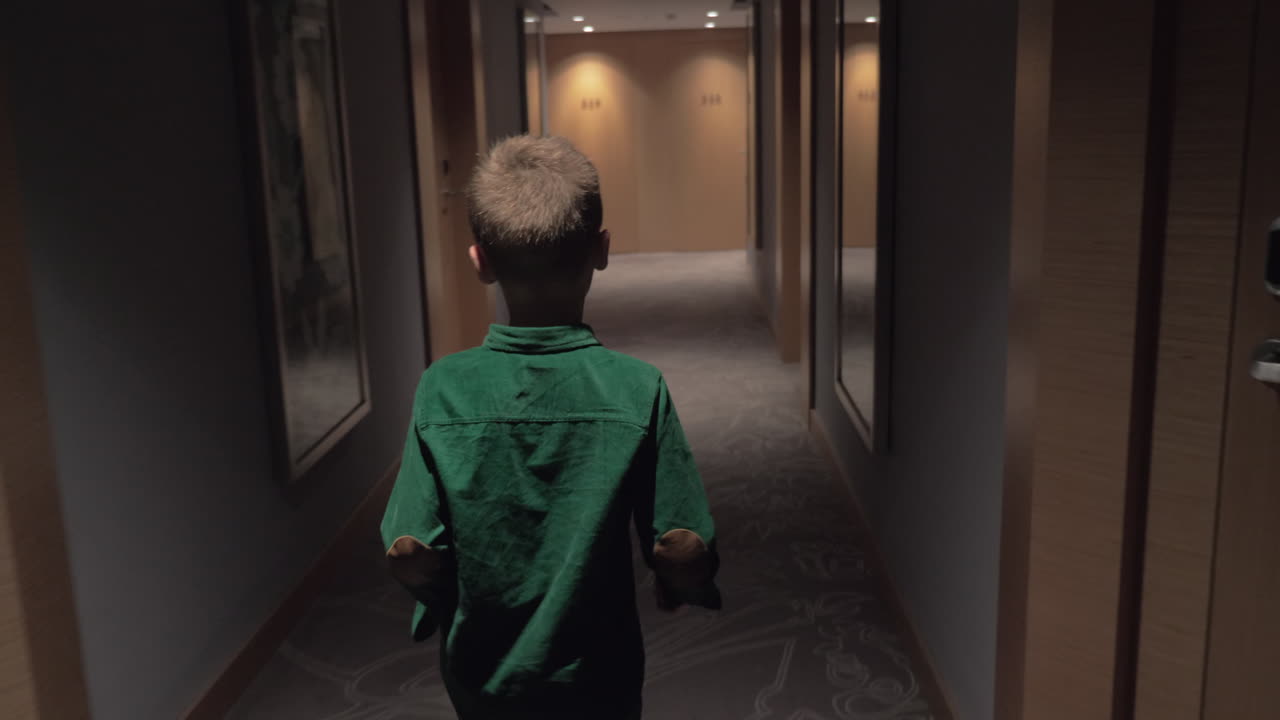Child walking in hotel hall and opening room door with keycard