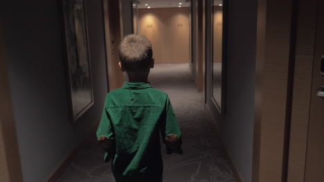 niño caminando en el pasillo del hotel y abriendo la puerta de la habitación con una tarjeta clave