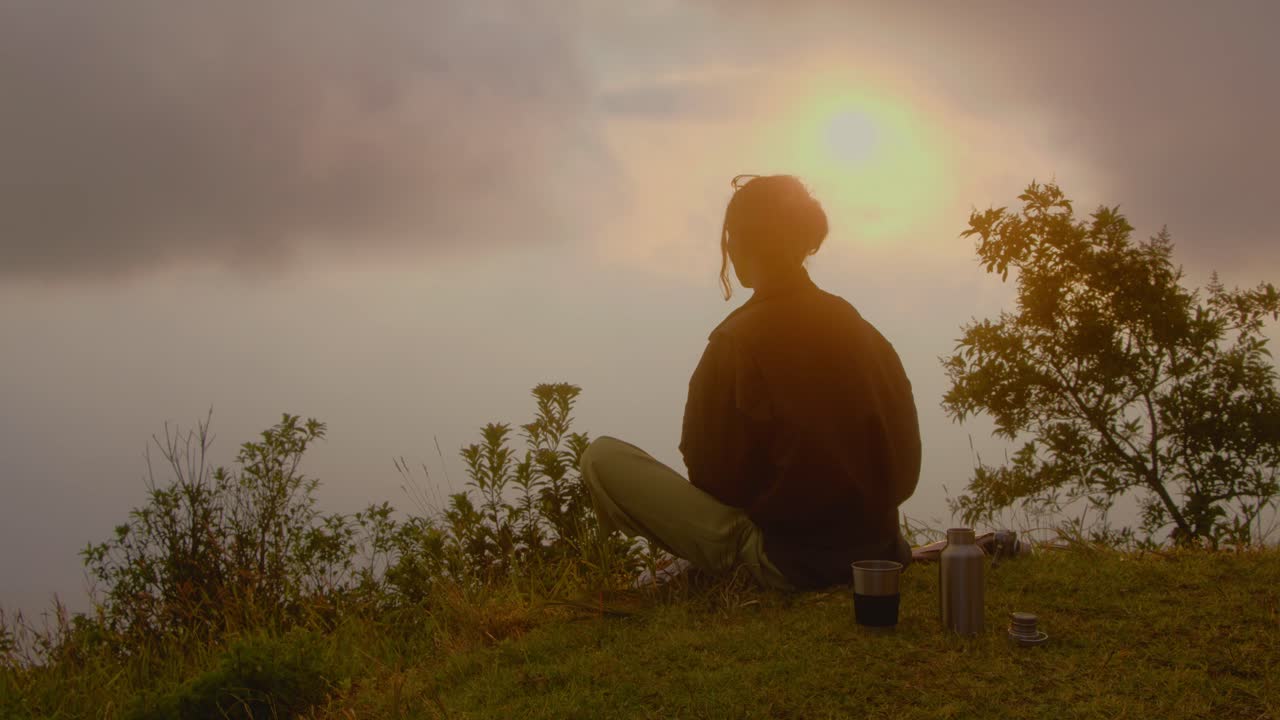 Person enjoying a serene sunset view from a hilltop