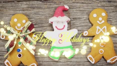 Animation-of-happy-holidays-text-over-christmas-cookies-on-wooden-background