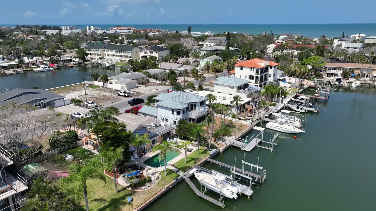 Waterfront community in Indian Rocks, FL, homes with docks along a serene waterway. Boats are moored and area is lush with greenery, showcasing blend of residential and natural beauty. Aerial top down