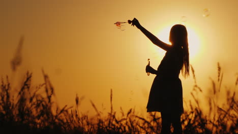 niño despreocupado jugando con pompas de jabón al atardecer de verano y concepto de infancia feliz
