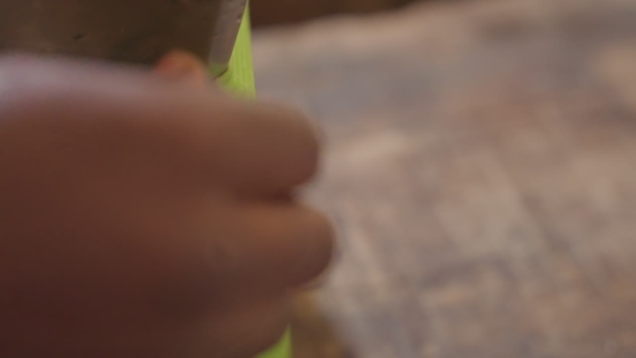 Primer plano de una mano apretando una abrazadera en un banco de trabajo, escena de carpintería DIY con una abrazadera verde, vetas de madera y aserrín, dedos concentrados ajustando el tornillo, aprendiz de carpintero practicando ensamblaje táctil y acabado