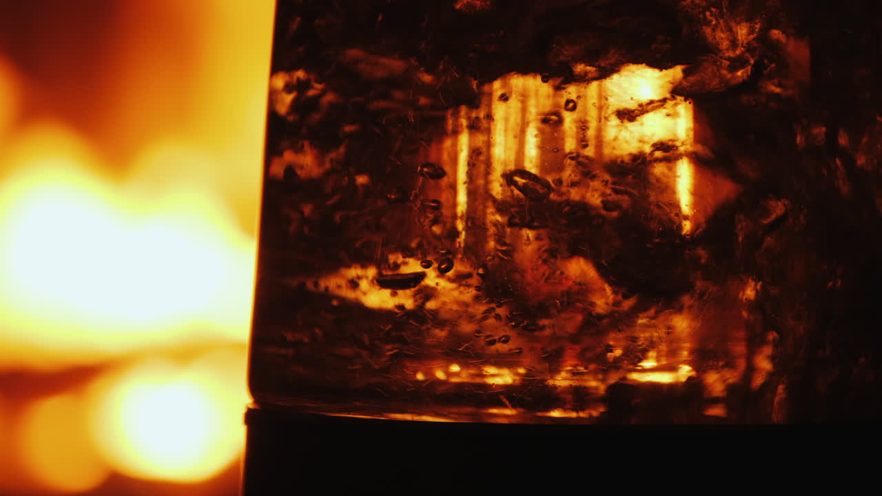 벽난로에 열린 불의 배경에 있는 투명한 유리 제품에 끓는 물