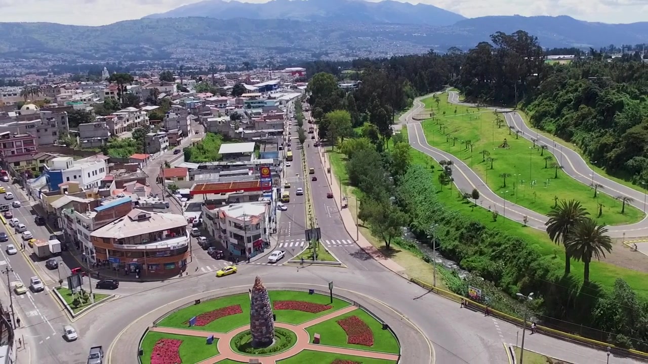 Uma cidade movimentada com rotatória ao lado de um parque no Equador.