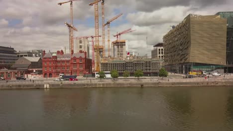 panning shot of construction site and anglo irish bank with vehicles passing by on the river liffey