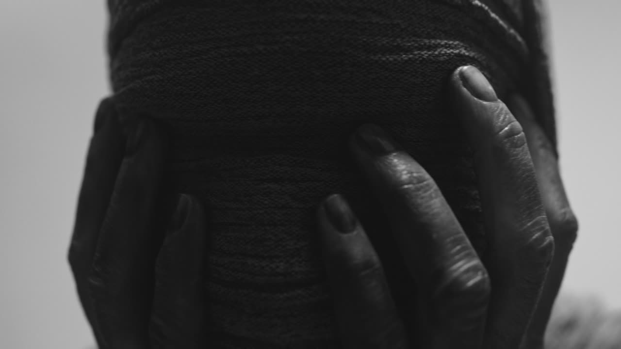 A mummified woman against the bright background in keeps her hands on her face the powerful pose full of despair