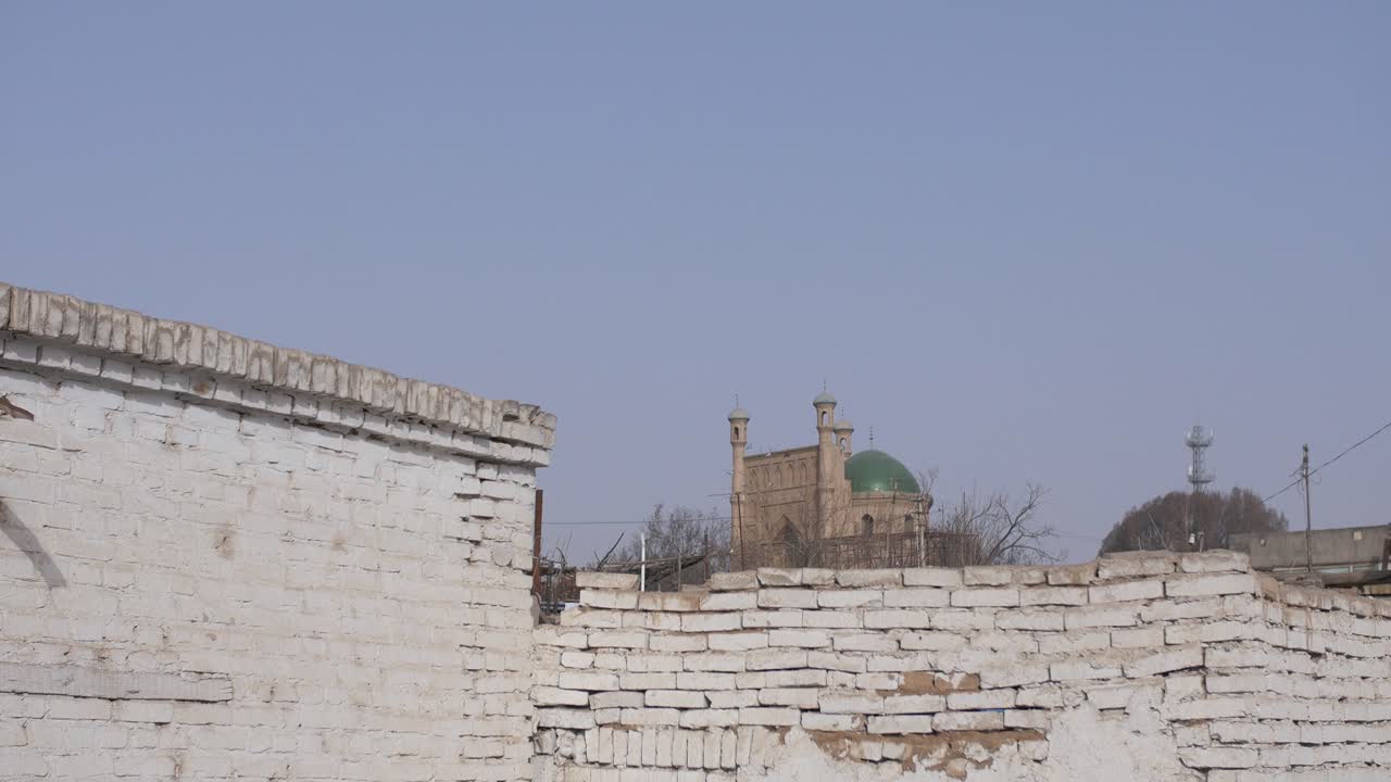 Kuqa, Xinjiang, Cina - Moschea Uigura dietro il vecchio muro bianco in una giornata di sole splendente - Campo lungo