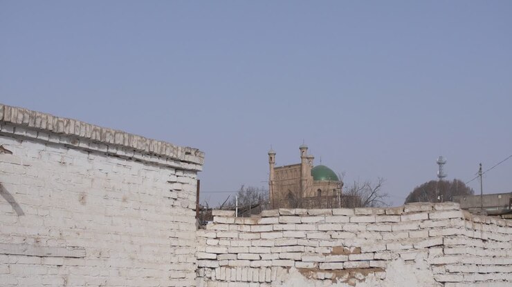 Kuqa, Xinjiang, Cina - Moschea Uigura dietro il vecchio muro bianco in una giornata di sole splendente - Campo lungo
