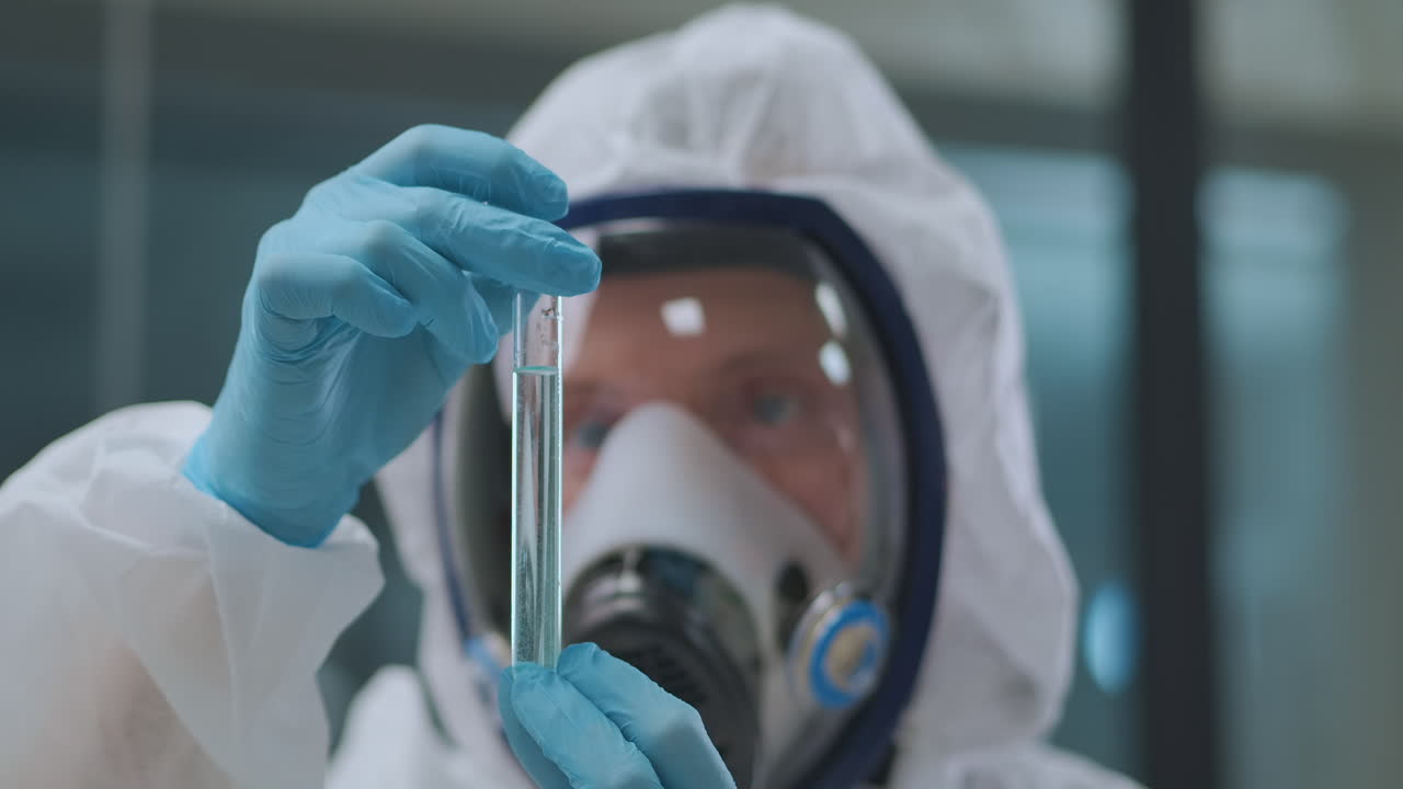 chimico sta lavorando con sostanze chimiche pericolose in laboratorio scienziato è vestito con abito protettivo e maschera primo piano del viso e del tubo di prova
