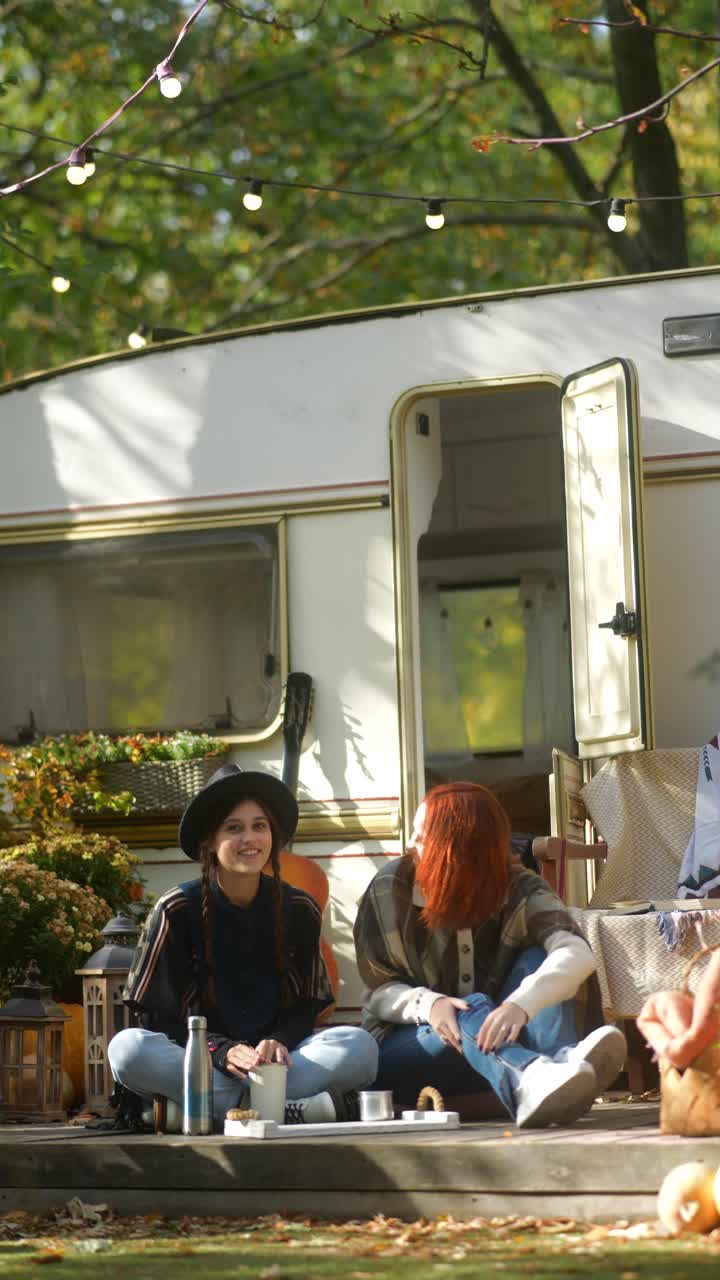 두 친구 가 캠핑 트레일러 에서 야외 에서 커피 를 마시고 있다