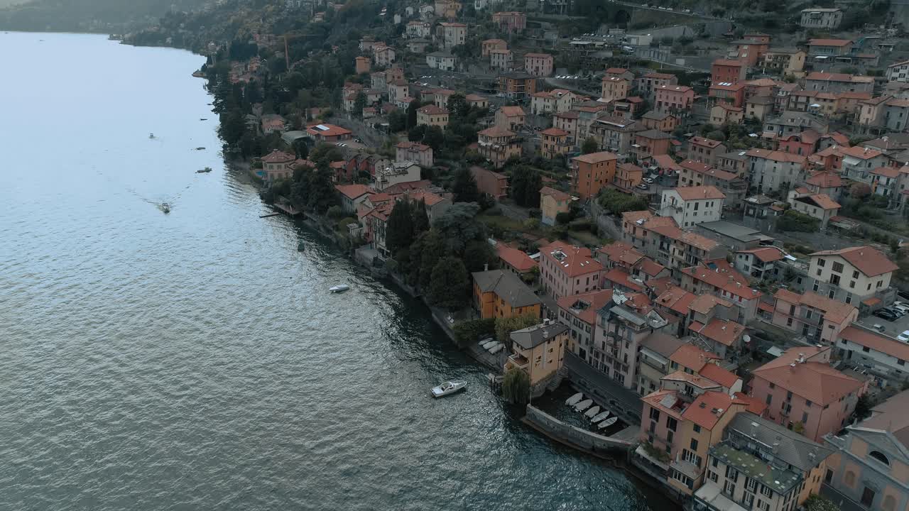 inclinación aérea sobre el lado del pueblo del lago de como que muestra la arquitectura de las casas mediterráneas con las montañas alp en el fondo - moody cinematic