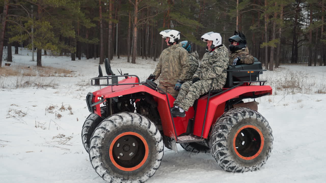 ATV rosso con piloti in mimetica, tre piloti con casco eseguono una manovra coordinata su una radura innevata, le gomme girano in derapata controllata, esercitazione di squadra, allenamento outdoor impegnativo, movimento ad alta energia.