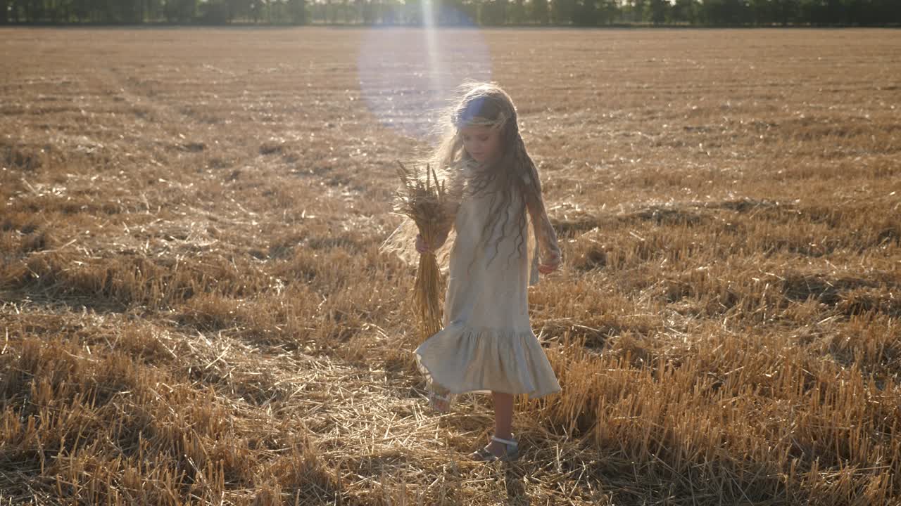 una niña triste y seria un niño está de pie en un campo de trigo cortado