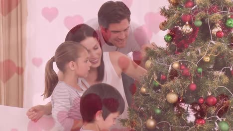 animación de la familia decorando el árbol de navidad contra el corazón rosa