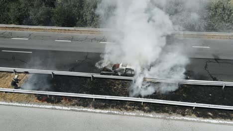 firefighters extinguish burning car on highway following serious car accident on hot summer day aerial view. fire truck came to rescue. flow of cars on track. problem is on the road. traffic incident