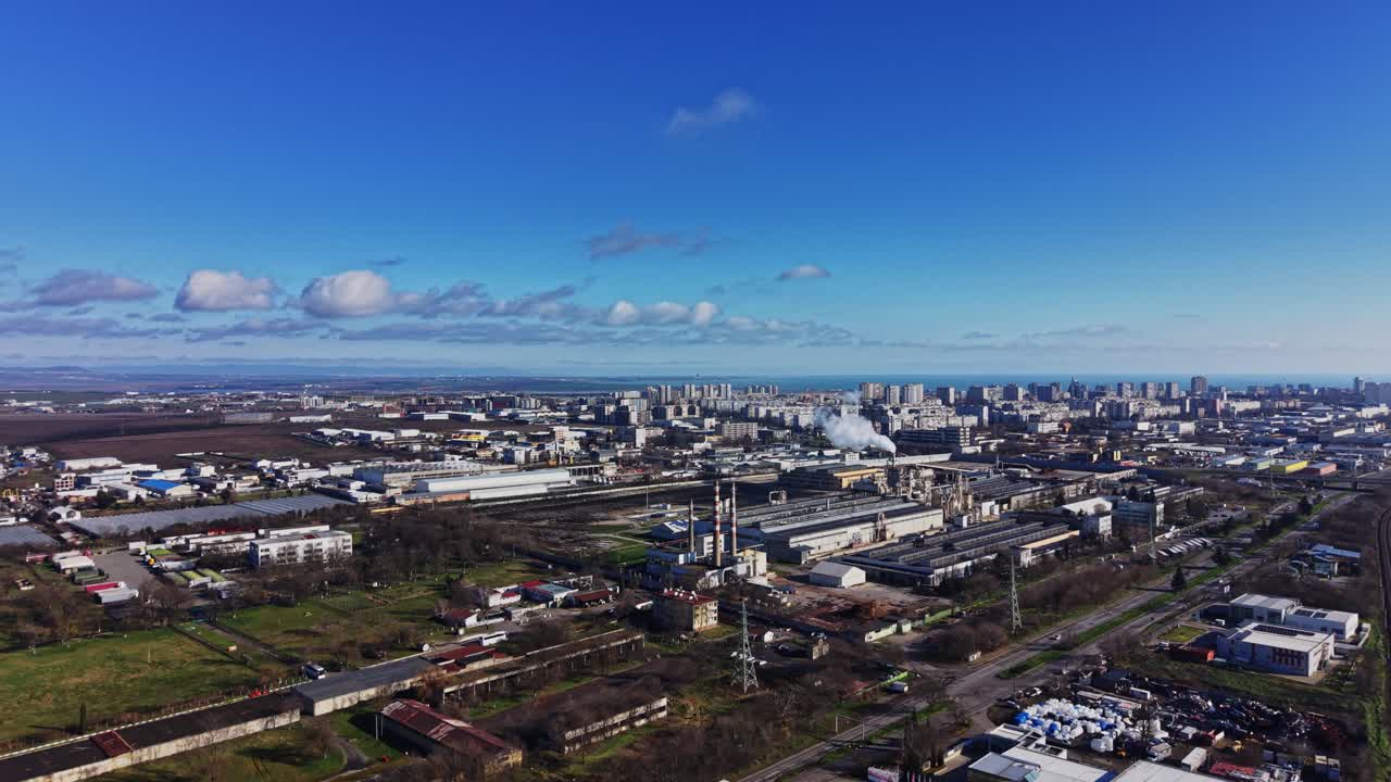 澄み切った空の下、工業地帯と建物が並ぶ都市景観