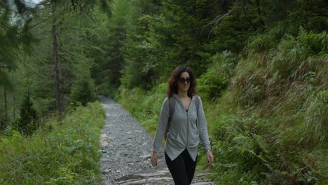 mujer con gafas de sol y mochila camina por el sendero de montaña en alpe ventina