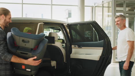 hombre instalando un asiento de coche para bebés en un suv negro