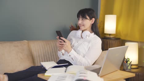 Woman-lying-on-the-sofa-at-night-texting-on-the-phone.-Happy-and-in-good-spirits.